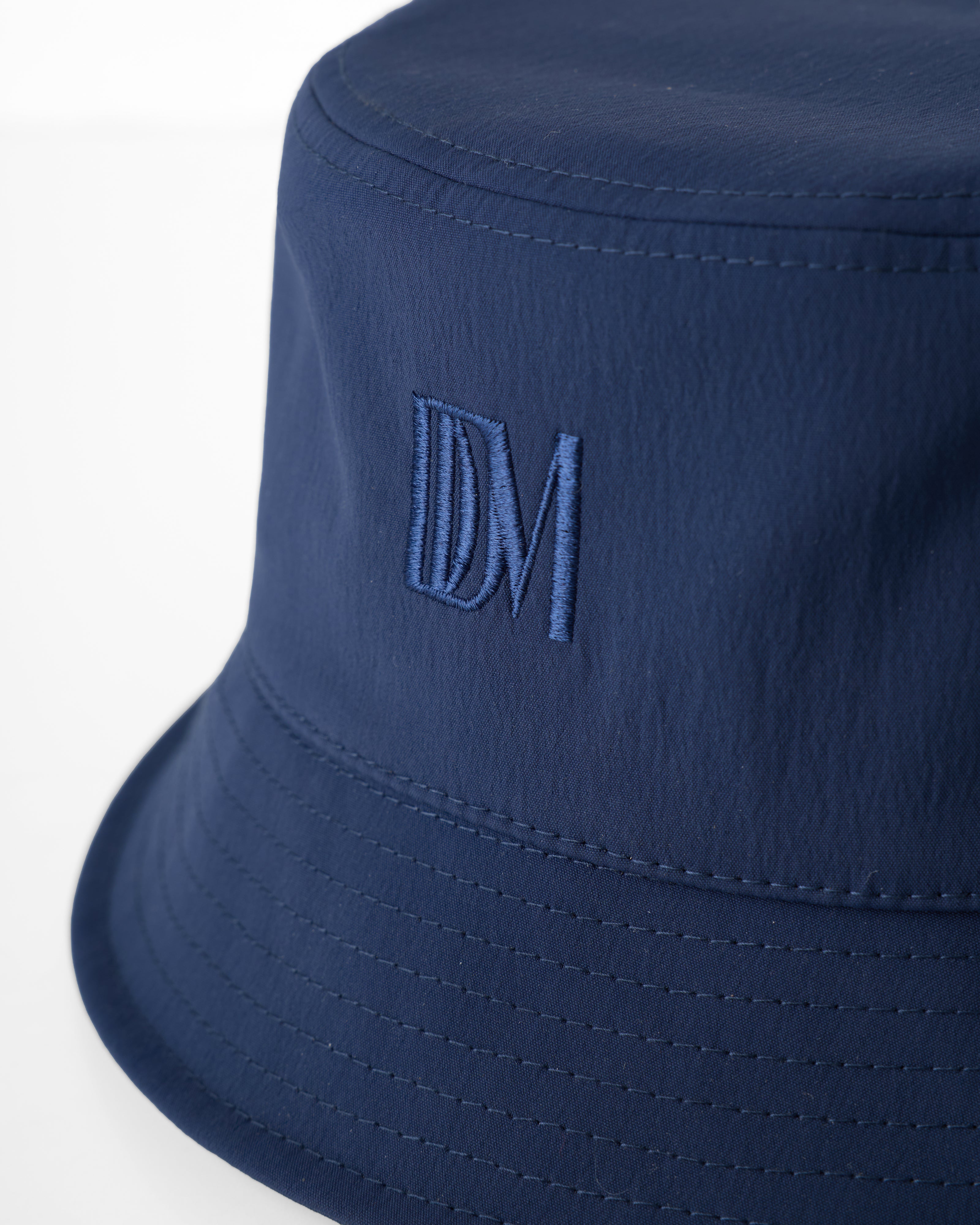 Close-up of The Bucket Hat - Anchor by Dandy Del Mar, featuring "DM" embroidered on the side in matching navy blue thread.