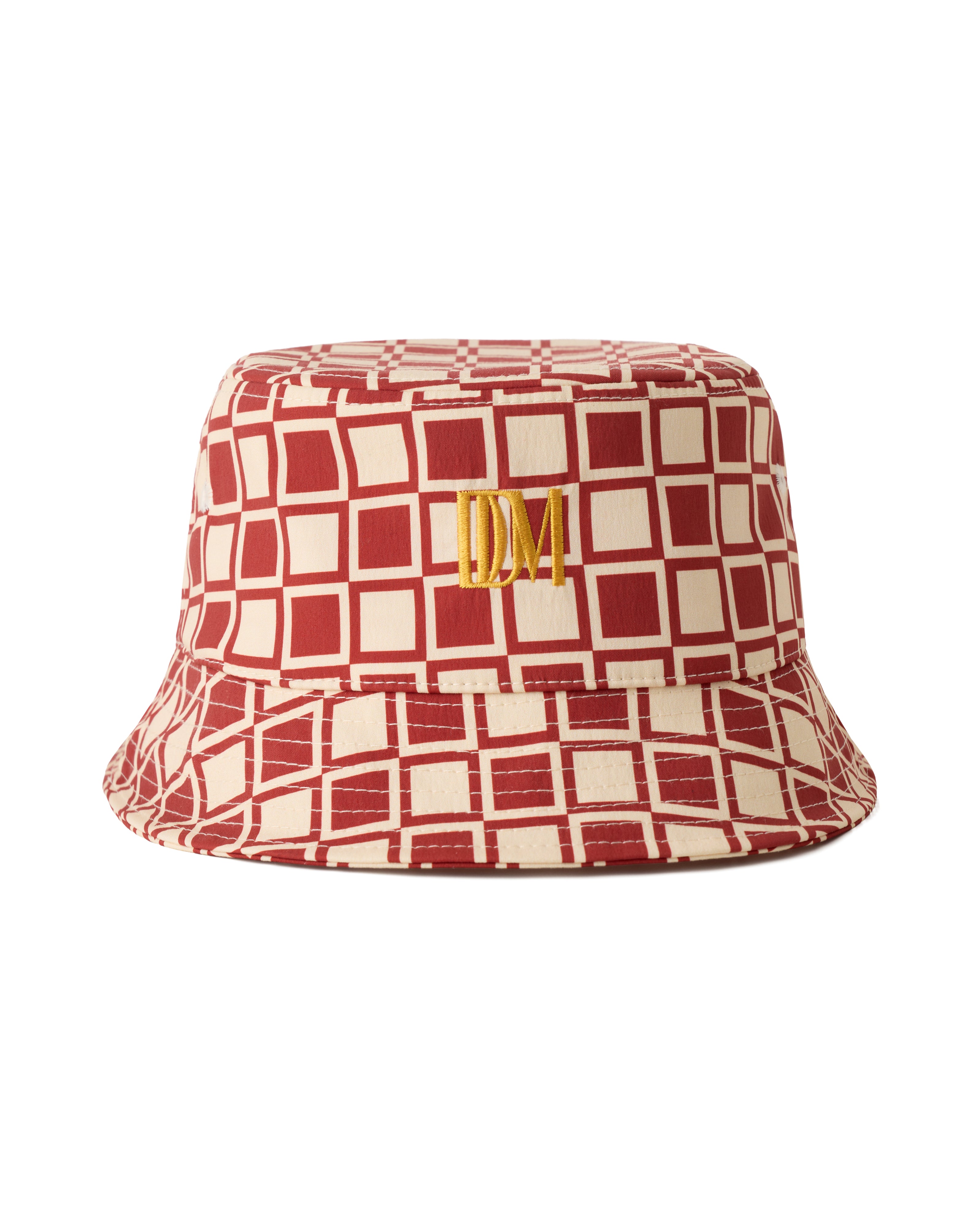 The Bucket Hat - Rouge by Dandy Del Mar features a red and beige geometric pattern and gold embroidered "DM" initials on the front.