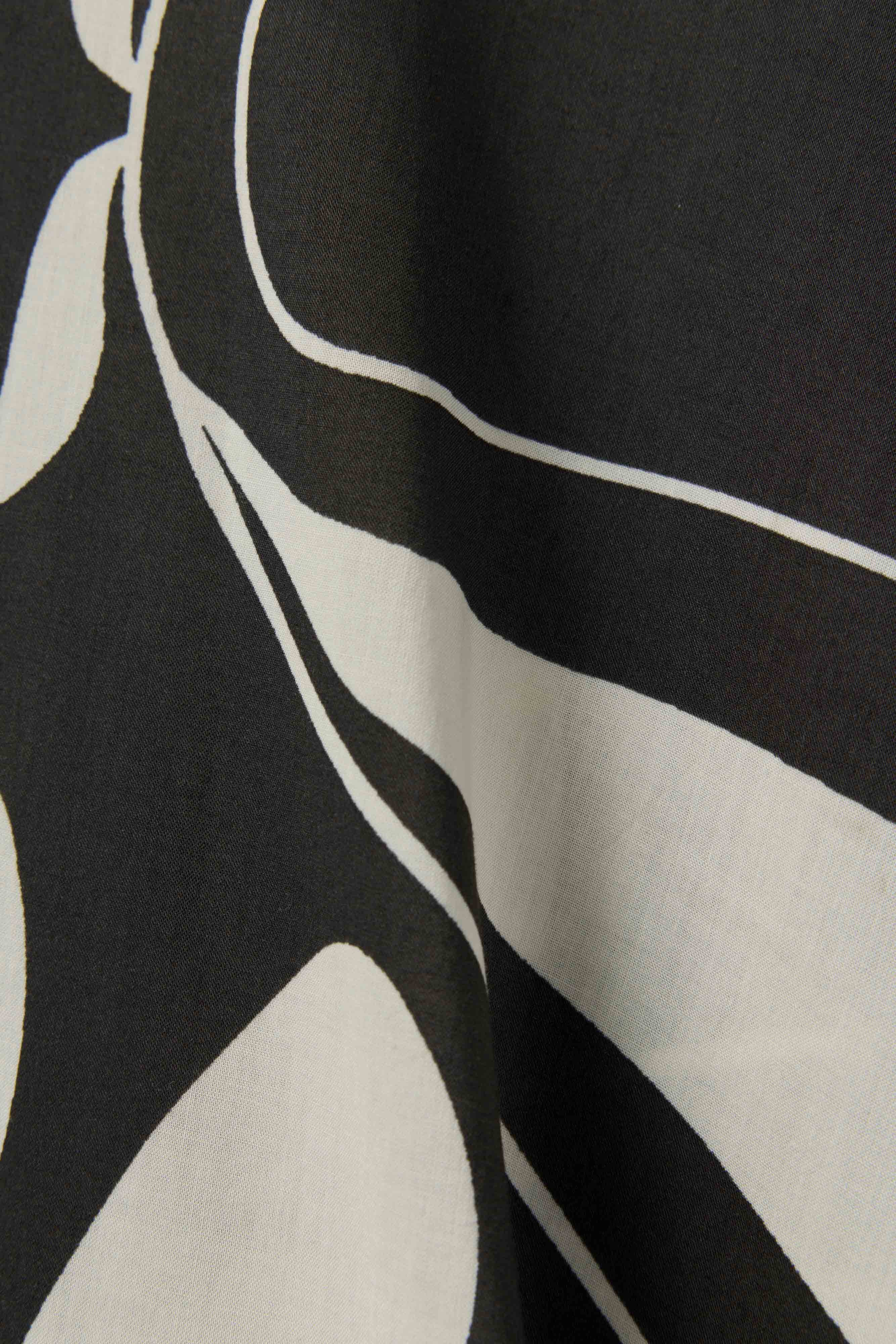 Close-up of The Tropea Kaftan - Albatross by Dandy Del Mar, featuring black fabric with bold white and cream abstract curves—ideal for a statement maxi dress or chic beachwear.