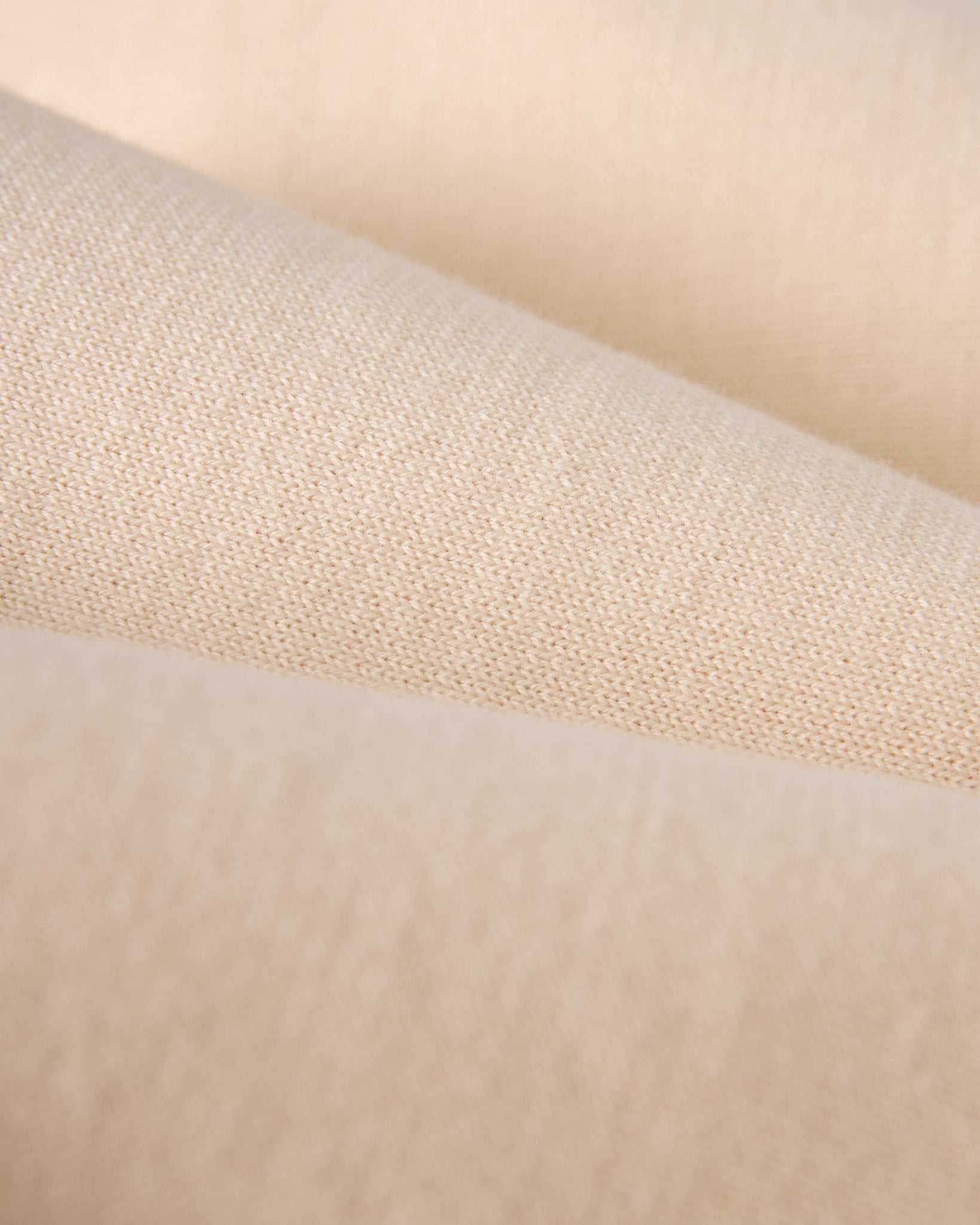 Close-up of The Grenada Sweater Knit Baseball Tee - Tierra by Dandy Del Mar, featuring beige lightweight cotton fabric with a soft texture and visible weave pattern, inspired by vintage-sport style.