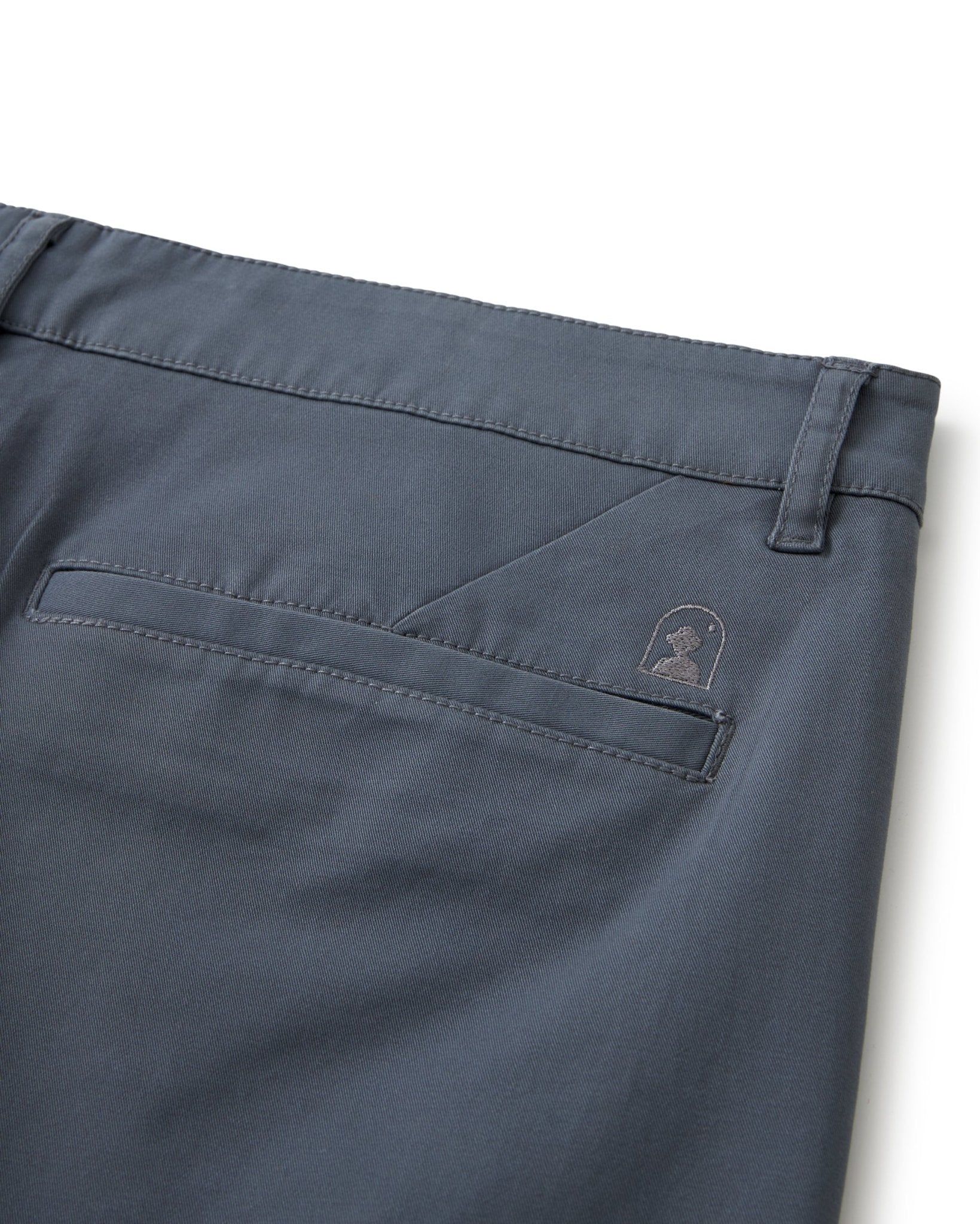 Close-up of the back pocket and waistband of The Rhodes Twill Shorts - Abyss by Dandy Del Mar, made from washed cotton twill, with a stitched logo above the pocket and a belt loop at the waistband.