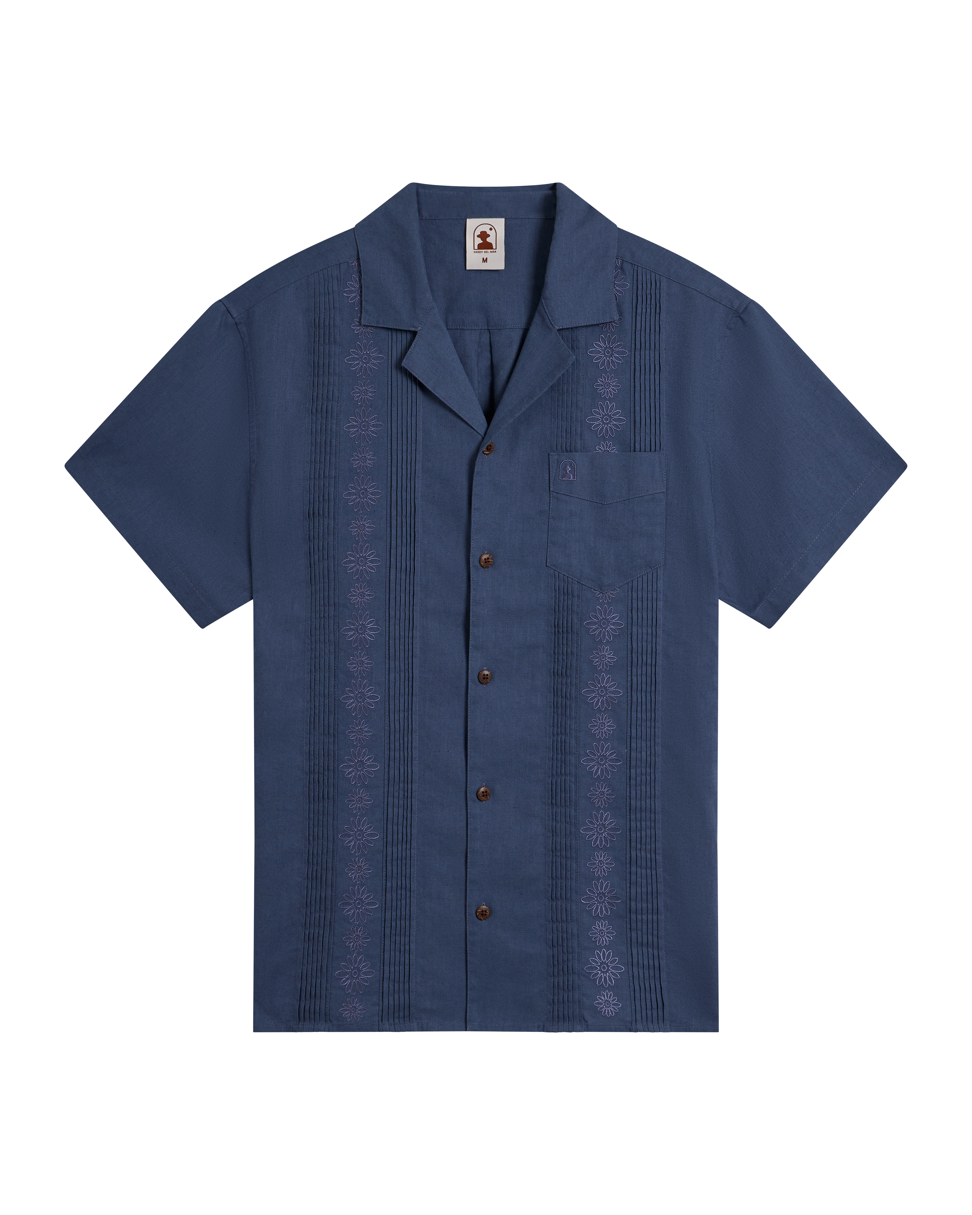 The Brisa Linen Shirt - Moontide by Dandy Del Mar features short sleeves, coconut shell buttons, a front pocket, and vertical embroidery in navy blue, shown against a plain black background.