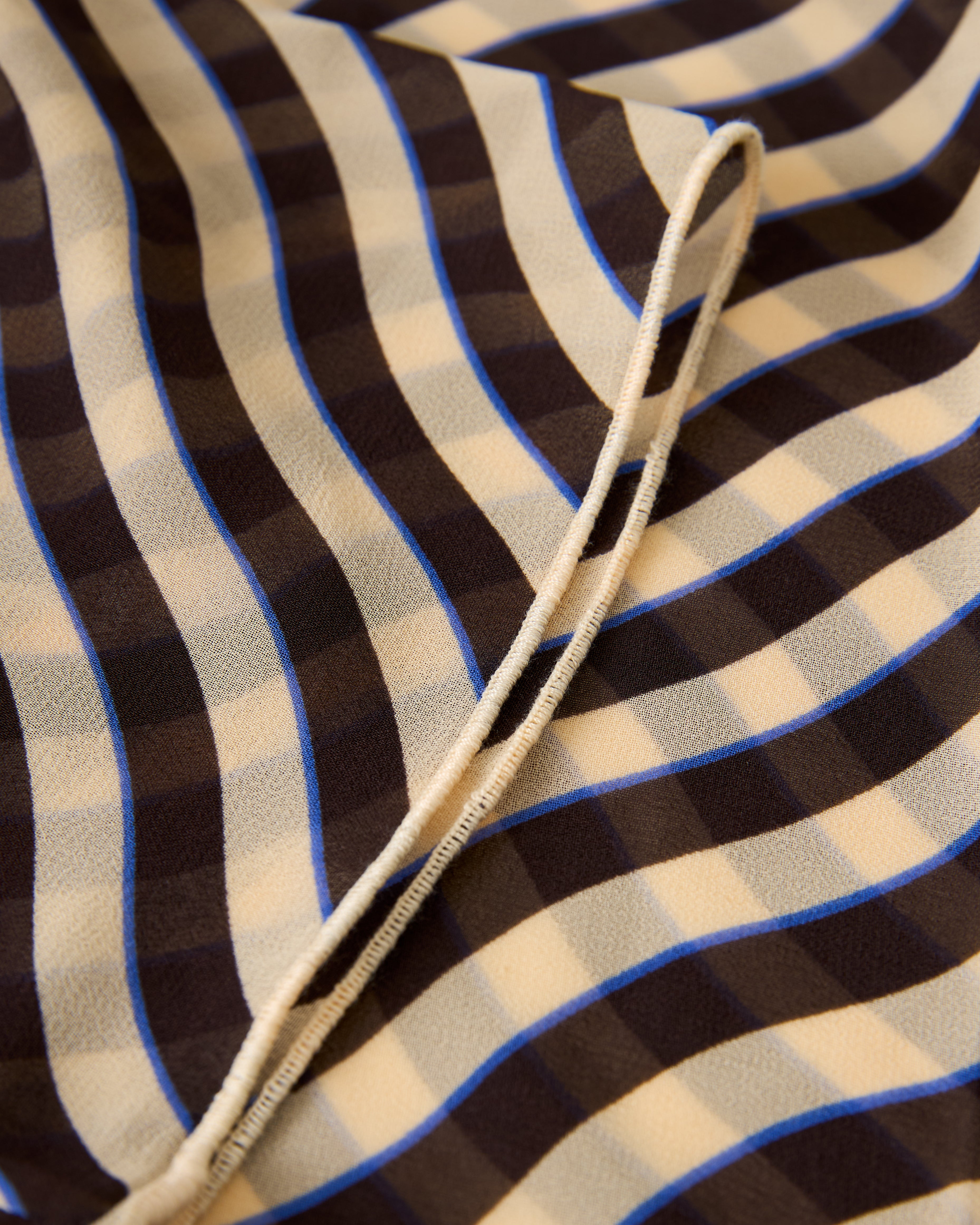 A close-up shows The Curacao Top - Tierra by Dandy Del Mar, featuring wavy beige, brown, and blue stripes with visible stitching along the edges.