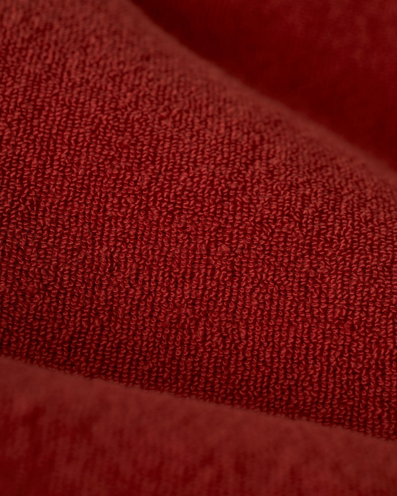 Close-up of The Gaucho Short - Rouge by Dandy Del Mar, highlighting the fibrous surface and subtle shadows of its red terry cloth fabric.