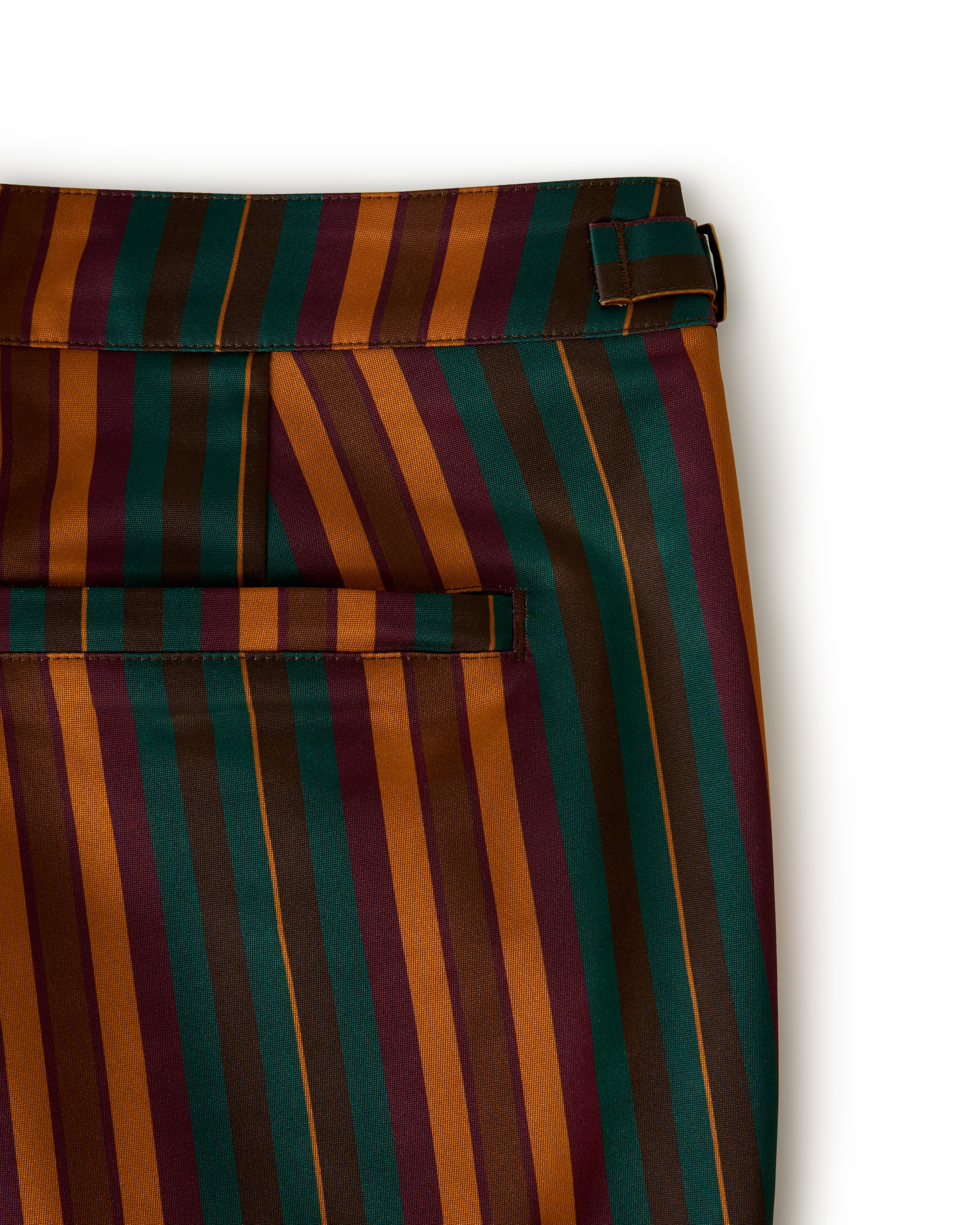 Close-up of The Mallorca Swim-Walk Short by Dandy Del Mar, featuring striped fabric in green, orange, red, and burnt sienna with a belt loop and horizontal back pocket. .