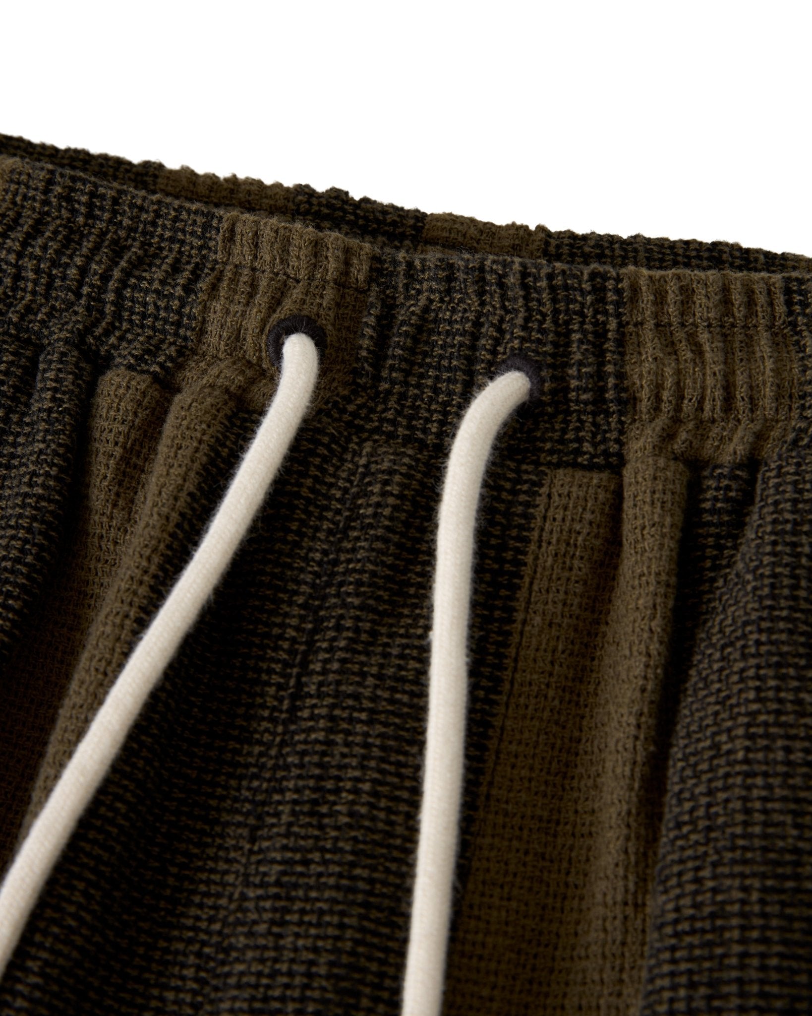 Close-up of The Palma Shorts - Onyx by Dandy Del Mar, featuring a textured dark brown waistband with white drawstrings through metal eyelets, showcasing the signature drawcord waist design.