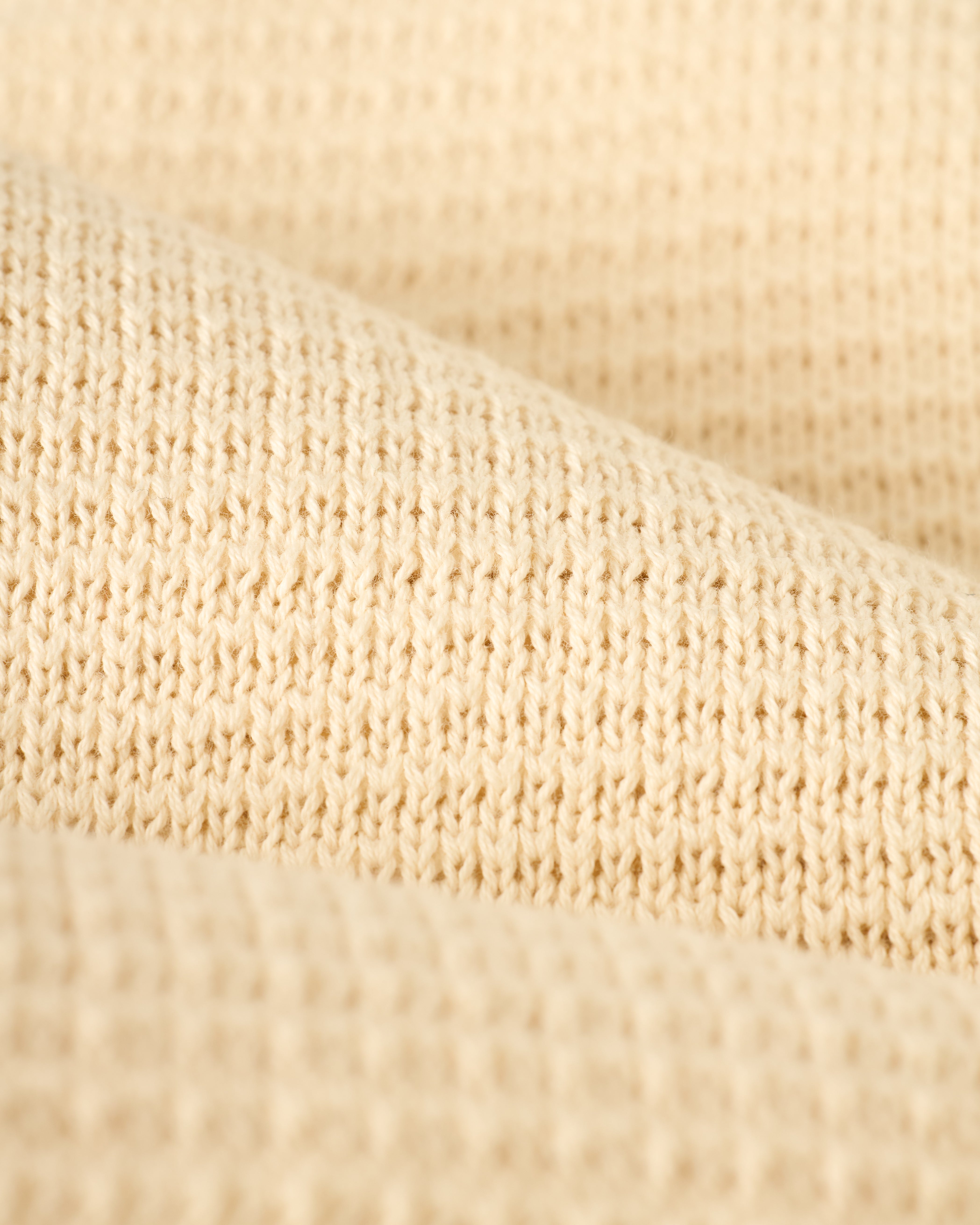 Close-up of The Sebastian Long Sleeve Polo in Vintage Ivory by Dandy Del Mar, highlighting its textured sweater-knit cotton and refined finish.