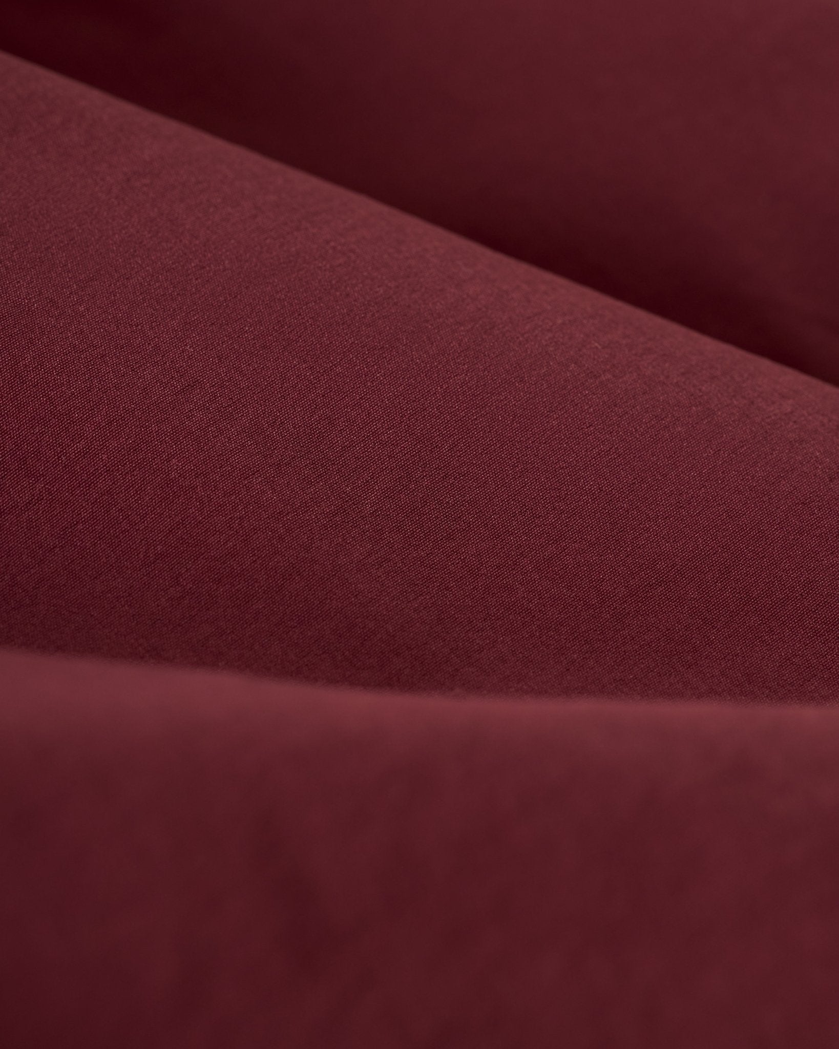 Close-up of the Stirata Swim Shorts in Bordeaux by Dandy Del Mar, showing their smooth, soft texture and gentle shadows. Features water-resistant fabric.