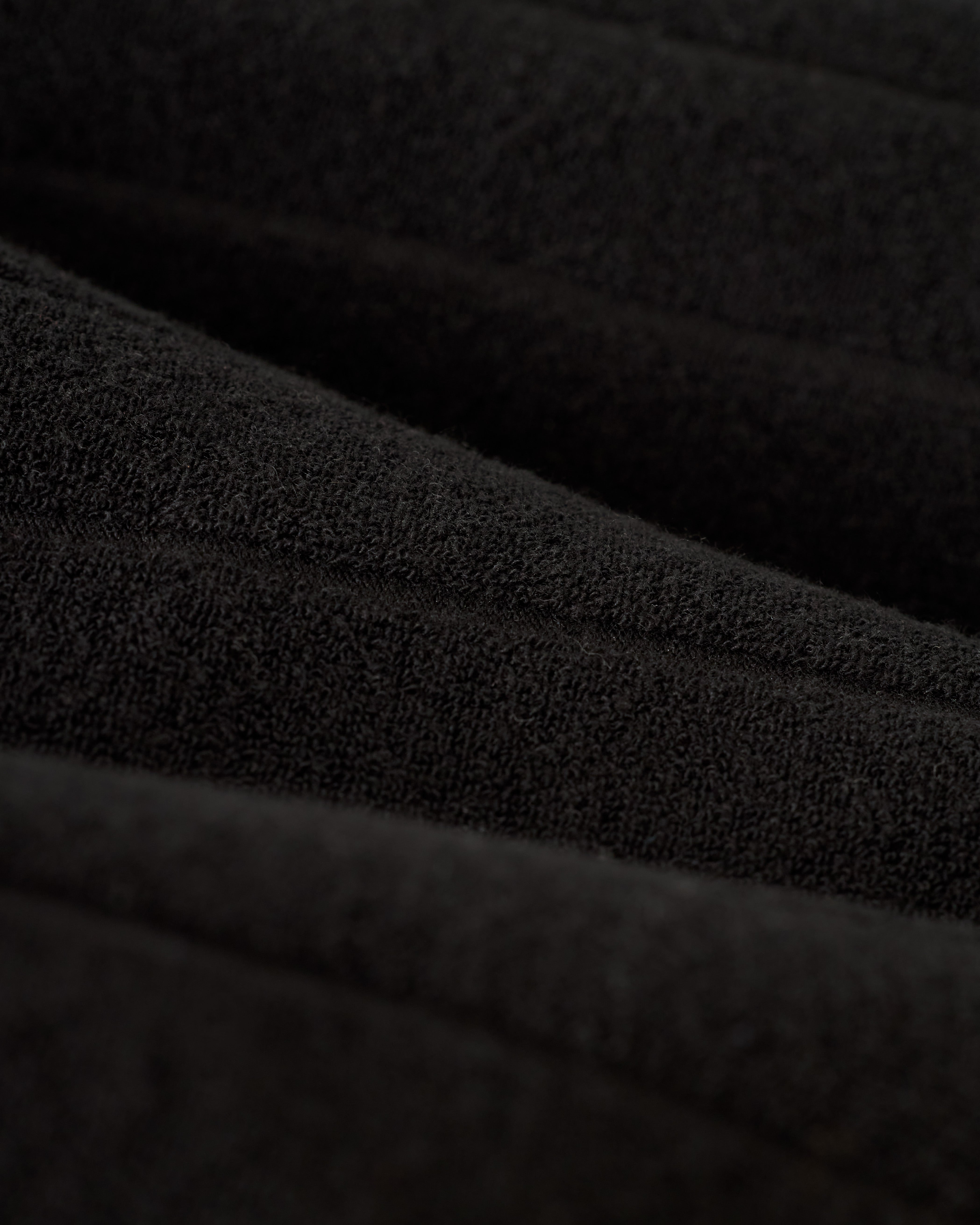 Close-up of The Tropez Jacquard Shirt - Onyx by Dandy Del Mar, featuring black terry cloth fabric with a soft, velvety appearance, gentle folds, and a subtle sheen.