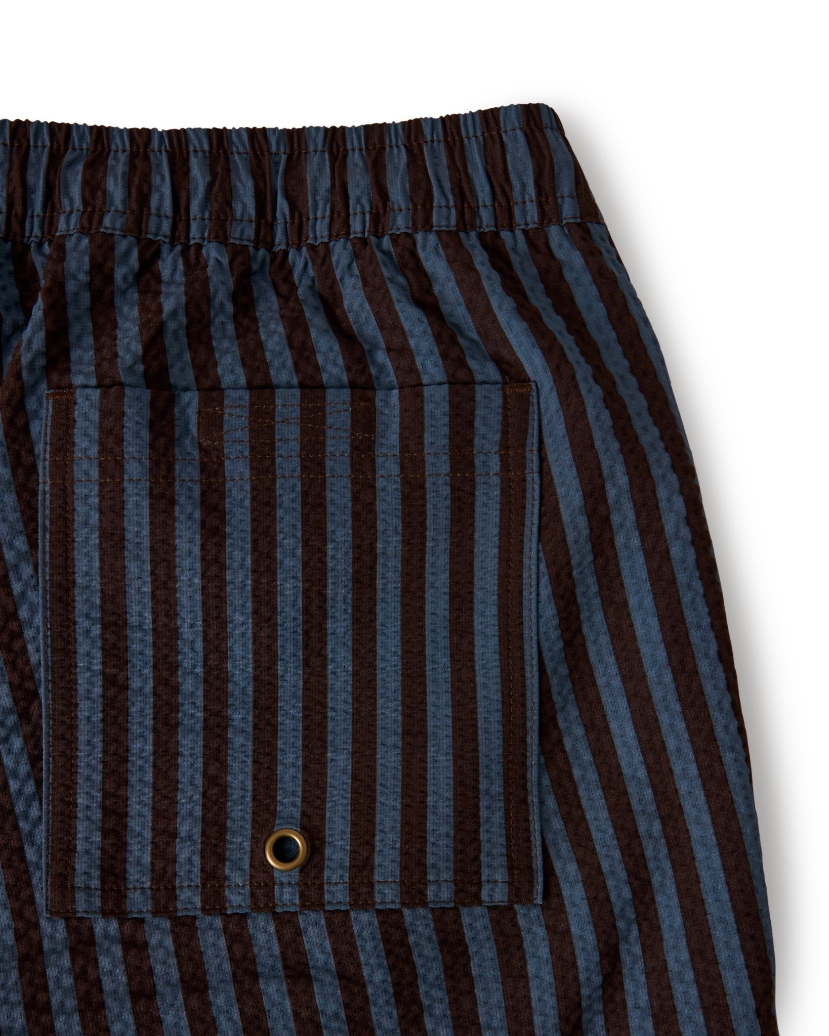 Close-up of The Ventura Volley Shorts - Moontide by Dandy Del Mar, showing the elastic waistband, pocket with metal grommet, and vertical brown and blue stripes.