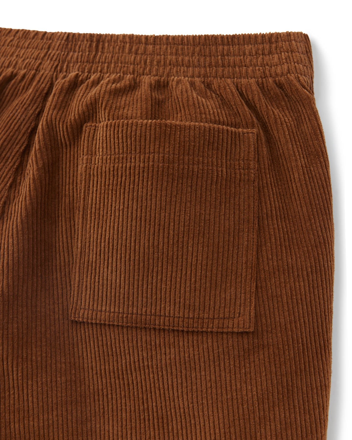 Close-up of The Corsica Corduroy Shorts in Tobacco by Dandy Del Mar, showcasing brown corduroy fabric with a patch pocket and elastic waistband—ideal for men’s casual or classic corduroy shorts.