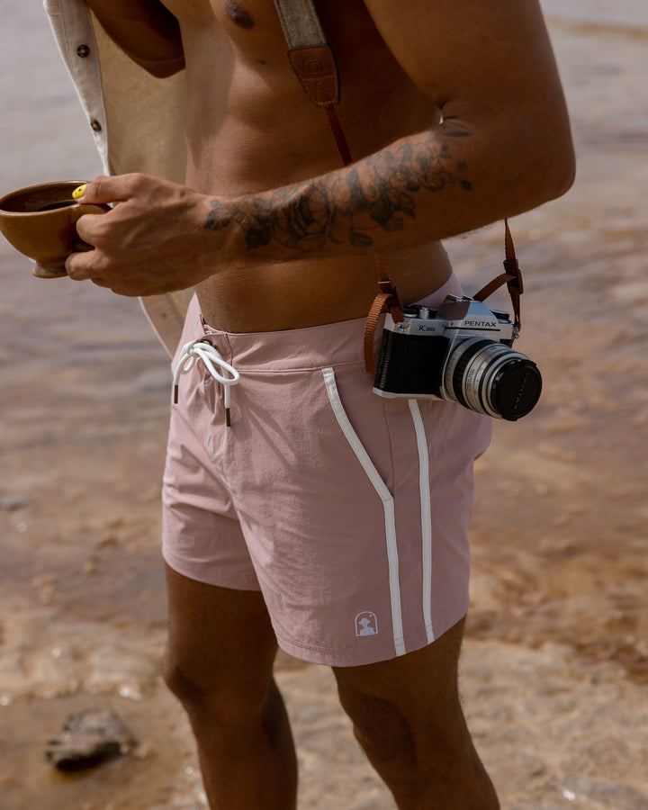 A man in The Stirata Swim Short - Rosado by Dandy Del Mar, equipped with a camera.