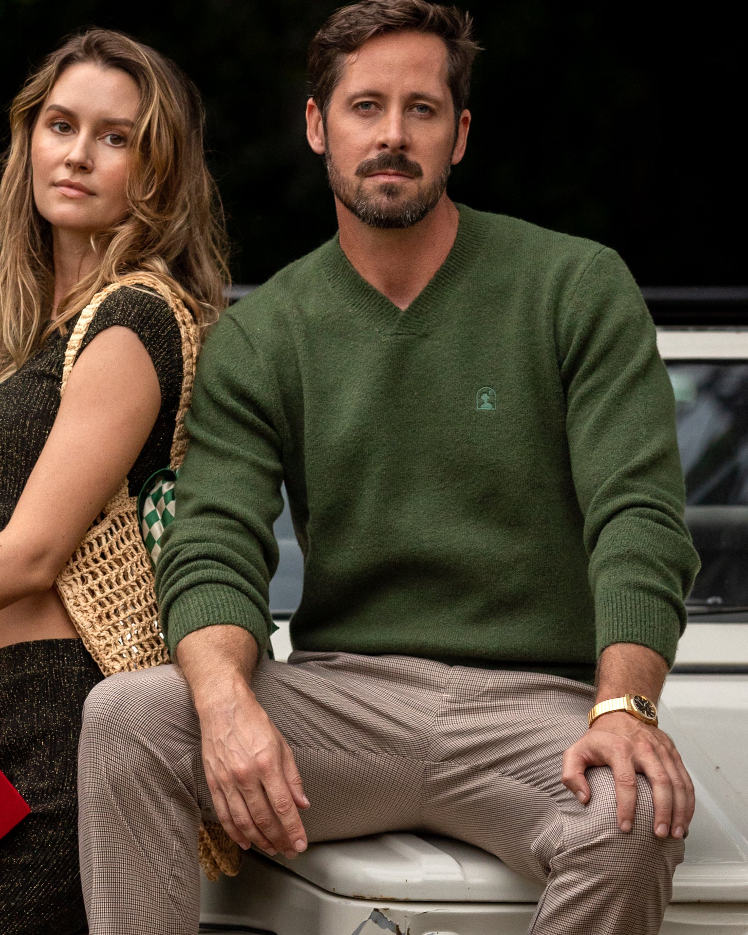 A man and woman wearing The Lima Sweaters by Selva, posing next to a car.