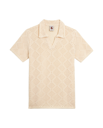 The Antibes Crochet Shirt by Dandy Del Mar in Vintage Ivory, a short-sleeve pullover polo with collar, V-neck, and diamond pattern, is displayed laid flat on a black background.