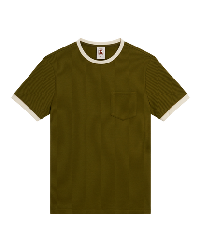The Cannes Waffle Knit Tee - Arbequina by Dandy Del Mar, a short-sleeve olive green waffle knit t-shirt with chest pocket and white-trimmed contrast collar and sleeves, is shown laid flat on a black background.