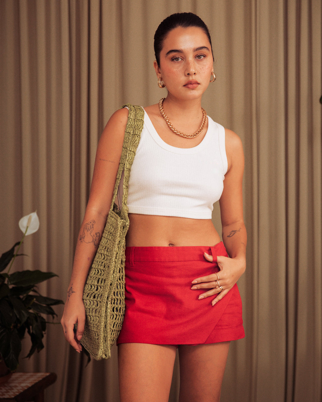 A woman wearing The Seine Rib Tank - Shell by Dandy Del Mar and a red skirt.