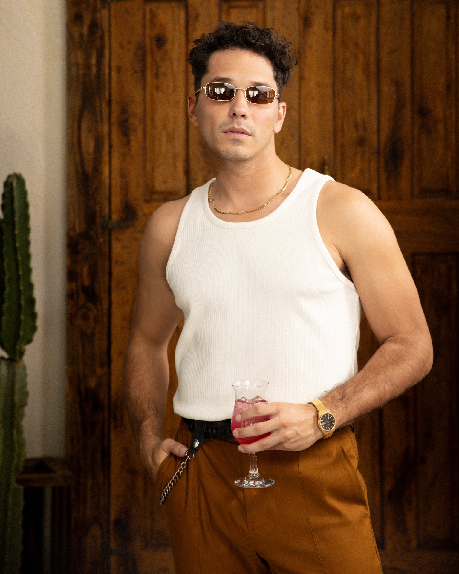 A man in a Dandy Del Mar Milan Rib Tank - Shell holding a drink and a cactus.