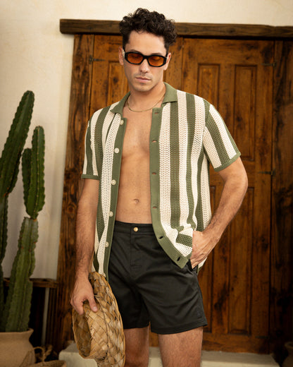 A man wearing The Dominica Crochet Shirt - Arbequina by Dandy Del Mar, standing next to a cactus.