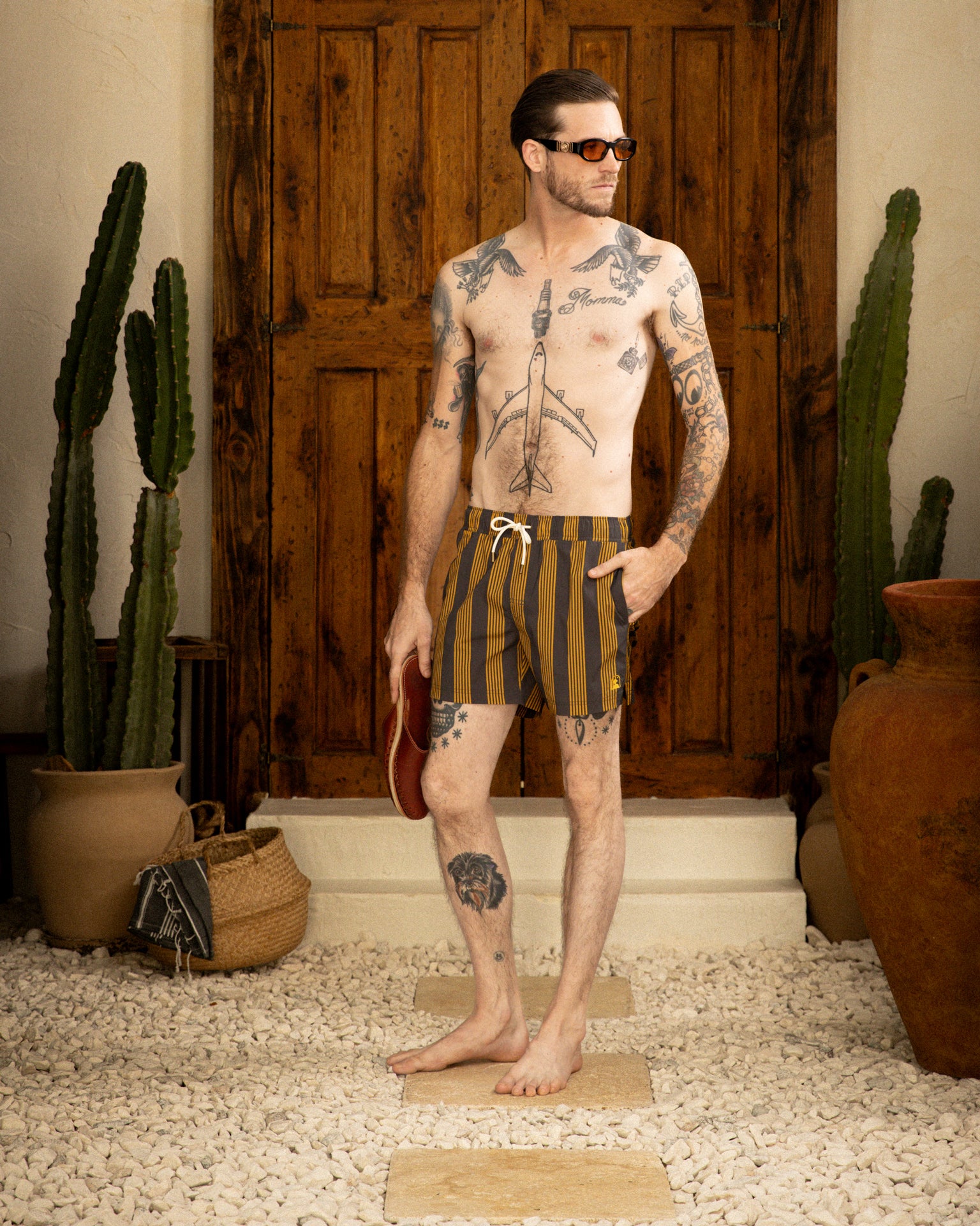 A man wearing Dandy Del Mar swim shorts with an elastic waist, standing in front of a cactus.