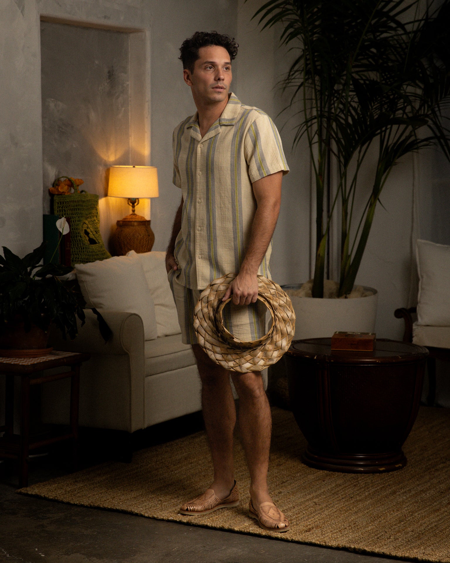 A man is standing in a living room holding The Corralejo Shirt - Ginger made by Dandy Del Mar.