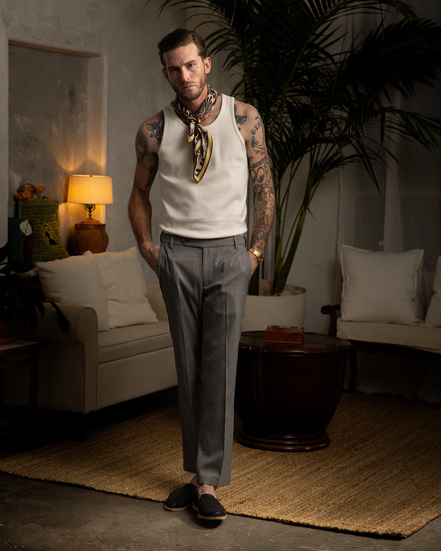 A Dandy Del Mar man wearing The Tresco Trouser - Albatross in a stylishly fit tank top in a living room.