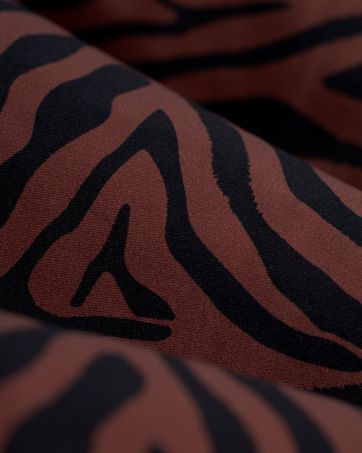 Close-up view of a fabric with a black and brown zebra stripe pattern, perfect for crafting The Gomera Bottom - Onyx by Dandy Del Mar.