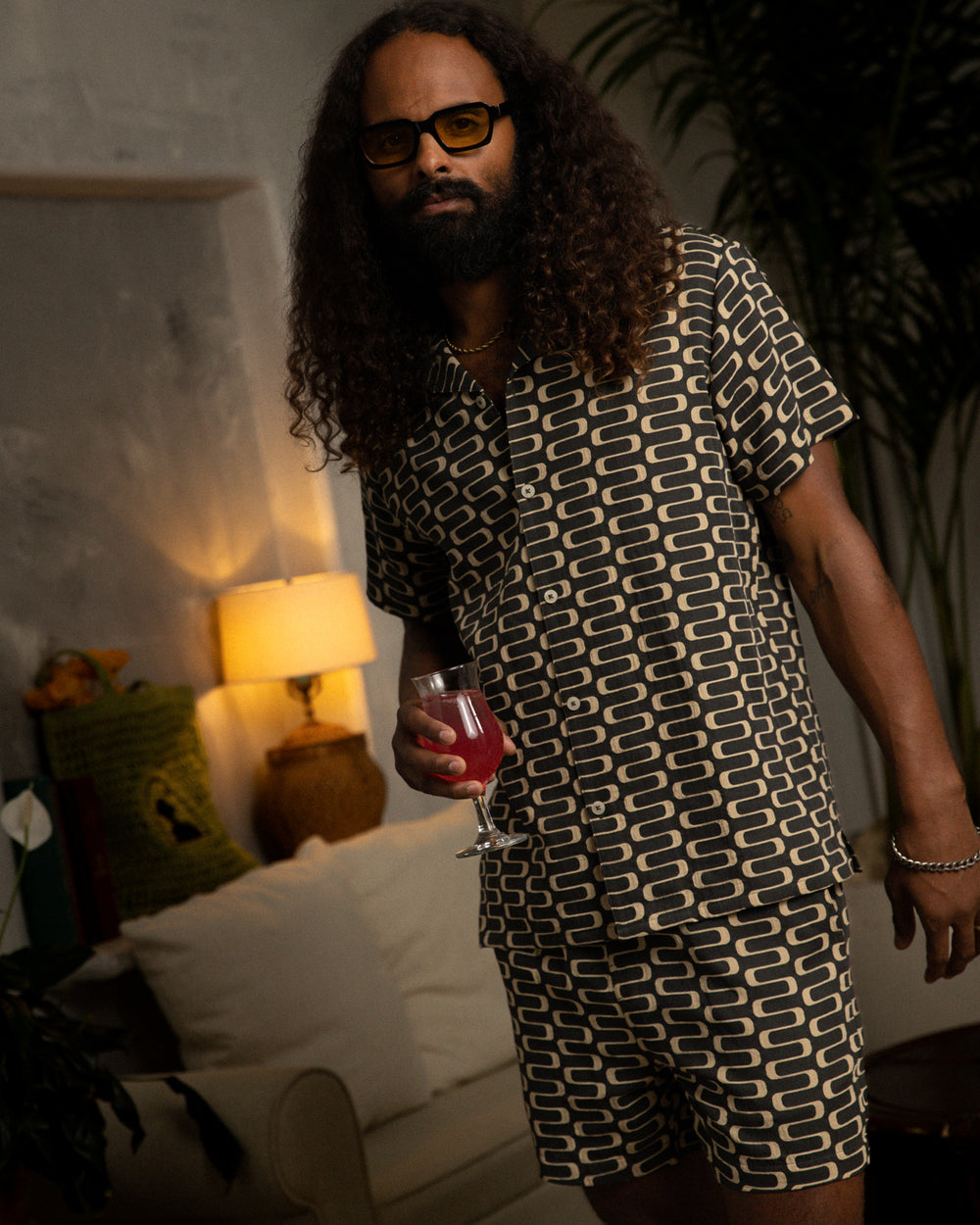 A man with long hair standing in a living room wearing a lightweight Dandy Del Mar - Truffle Shirt.