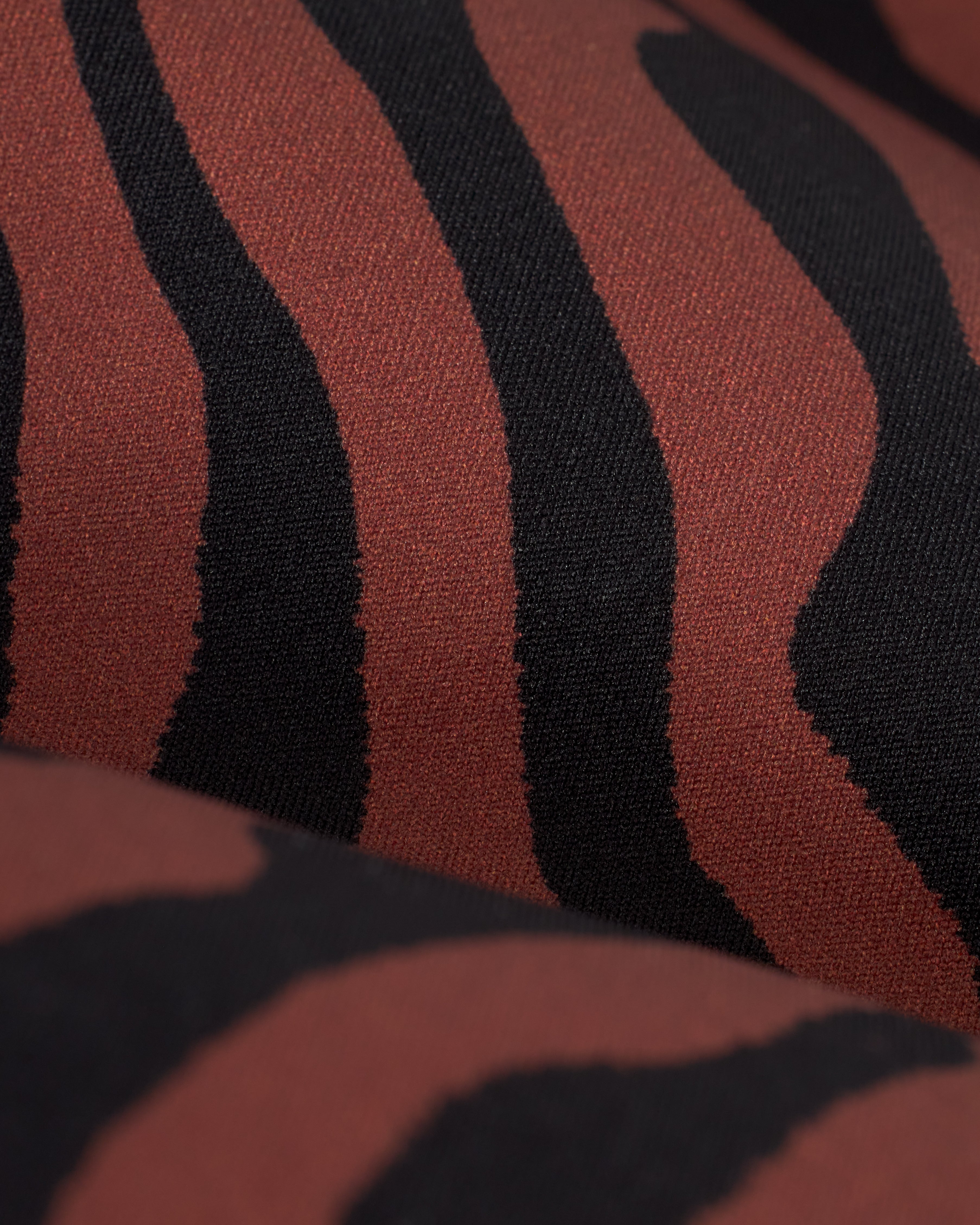 Close-up image of The Kokomo Bottom - Onyx by Dandy Del Mar, a low-rise bikini bottom made from sustainable recycled nylon, featuring a black and dark red zebra stripe print pattern.