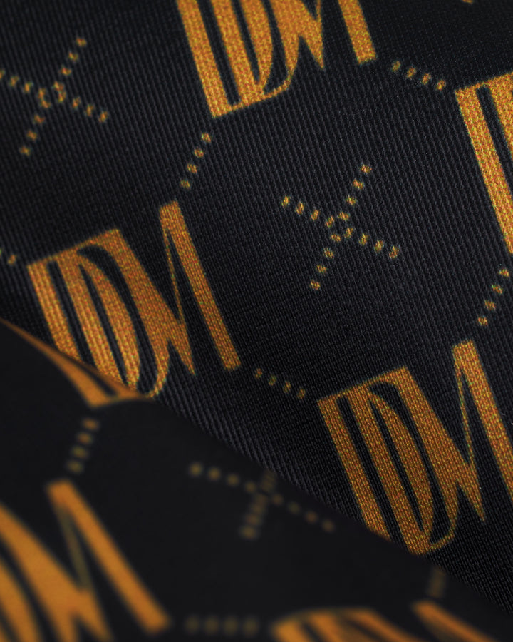 A black and gold tie with the Gomera Top - Oro Monogram by Dandy Del Mar.