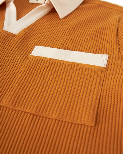 Close-up of Dandy Del Mar’s The Cannes Waffle Knit Polo Shirt in Burnt Sienna, showing its textured, ribbed waffle knit fabric with a white collar and chest pocket.