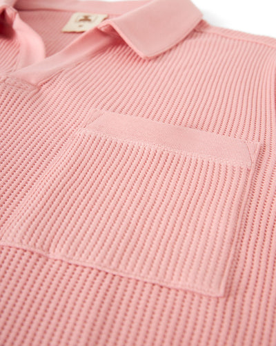 Close-up of The Cannes Waffle Knit Polo Shirt in Spanish Rose by Dandy Del Mar, crafted from textured waffle knit fabric with a chest pocket and a collar.