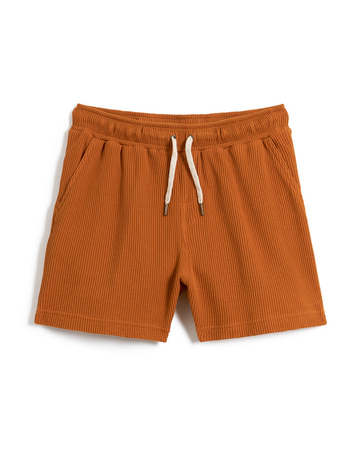 Description: The Dandy Del Mar Cannes Waffle Knit Shorts - Burnt Sienna feature brown ribbed knit shorts made of 100% cotton, complete with white drawstrings at the waistband and two side pockets.