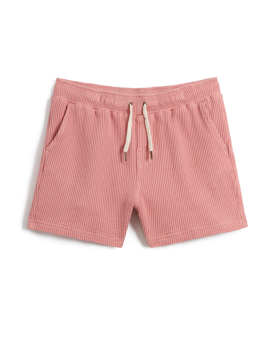 The Cannes Waffle Knit Shorts - Spanish Rose, crafted from waffle knit fabric, features an elastic waistband, drawstring, and side pockets. Laid flat against a white background, these pink shorts are made from 100% cotton for ultimate comfort by Dandy Del Mar.