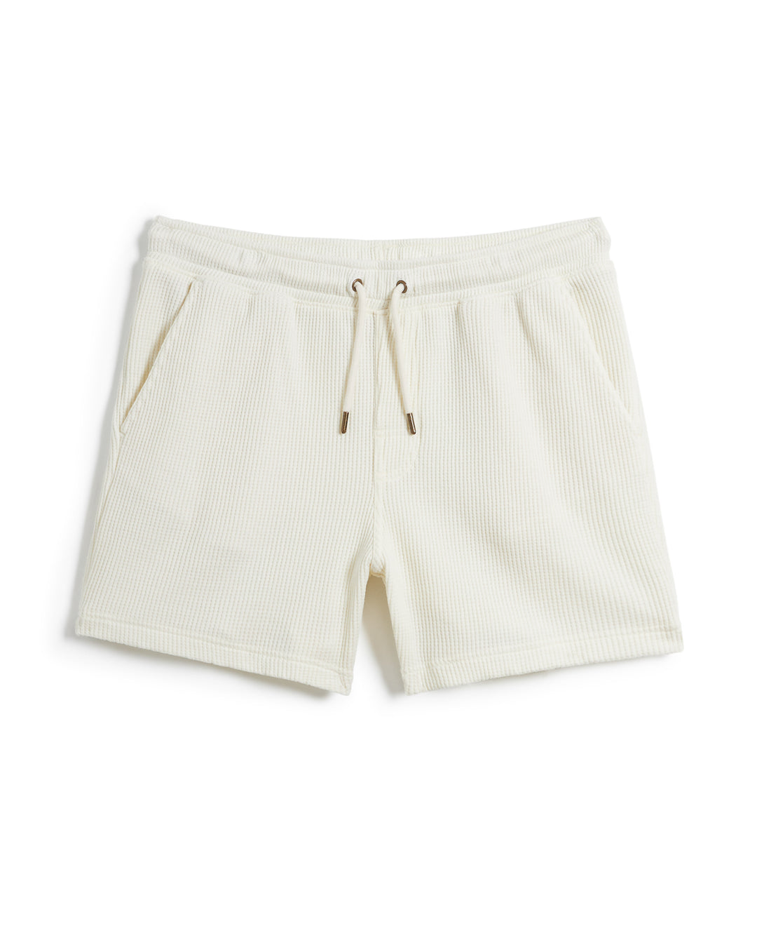 A pair of white Cannes shorts featuring an elastic waistband and a subtle striped texture, made from waffle knit fabric, displayed against a plain white background, is the **The Cannes Waffle Knit Shorts - Vintage Ivory** by **Dandy Del Mar**.