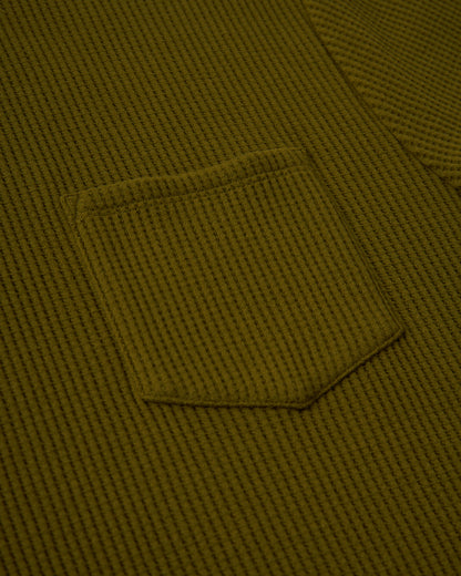 Close-up of The Cannes Waffle Knit Tee in Arbequina by Dandy Del Mar, showcasing its green waffle-knit fabric and small sewn pocket.