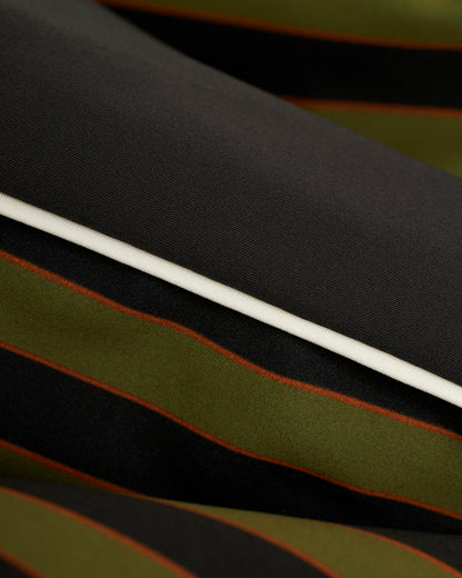 A close up of a Dandy Del Mar Cassis Square Cut Swim Brief - Arbequina, showcasing its black and green striped fabric.