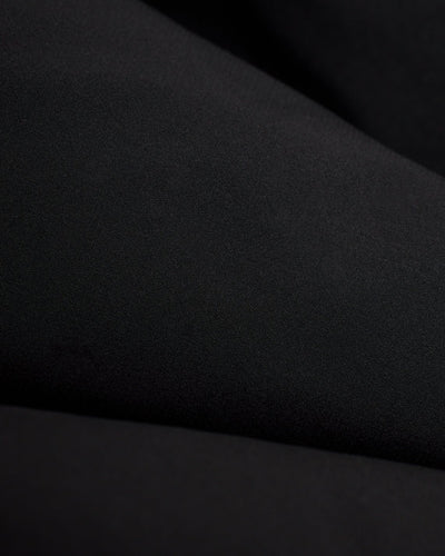 Close-up of The Cavoli Swim Shorts - Onyx by Dandy Del Mar, featuring black performance fabric with soft folds and a smooth texture, ideal for 4-way stretch boardshorts.