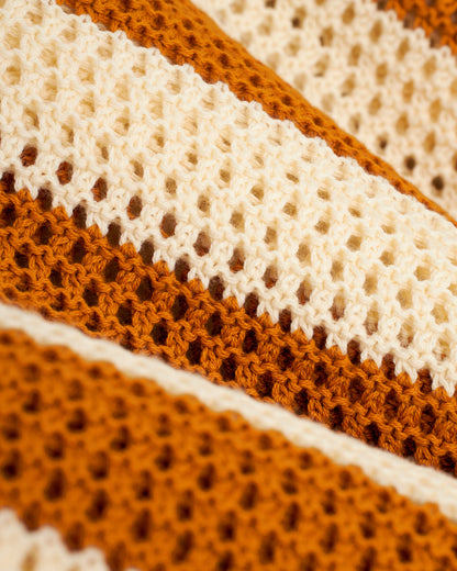 A close up of The Dominica Crochet Shirt - Burnt Sienna Stripe, a Dandy Del Mar cotton crocheted blanket.