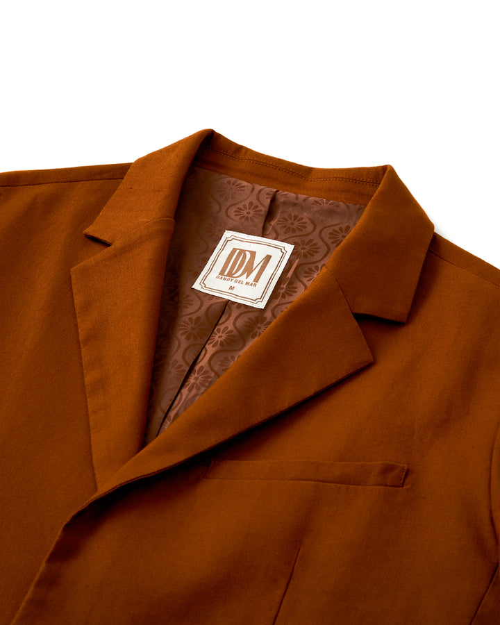 The Dandy Del Mar Brisa Linen Blazer - Sedona - a formal brown blazer adorned with a label. Perfect for night occasions and adding a touch of elegance to your outfit.