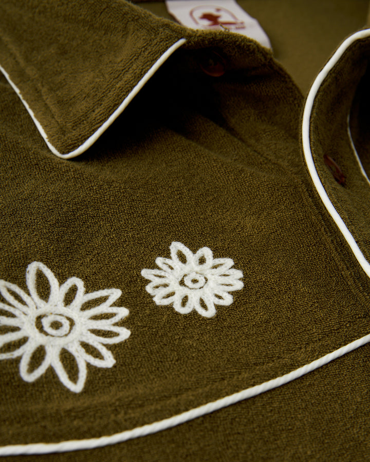 A close up of The Gaucho Shirt - Arbequina by Dandy Del Mar with white flowers on it.