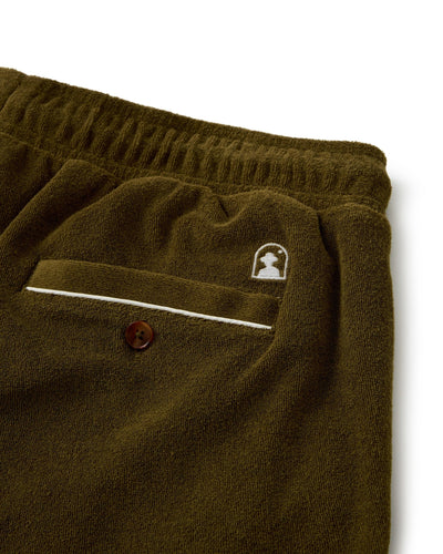 Close-up of Dandy Del Mar’s Gaucho Terry Cloth Shorts in Arbequina, featuring an elastic waistband, back pocket with button, white trim, and a small logo above the pocket—ideal for laid-back leisure.