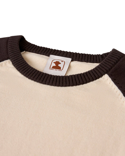 Close-up of The Grenada Knit Baseball Tee - Tierra by Dandy Del Mar, in beige and dark brown lightweight cotton, with a ribbed collar and interior brand tag for vintage-sport style.