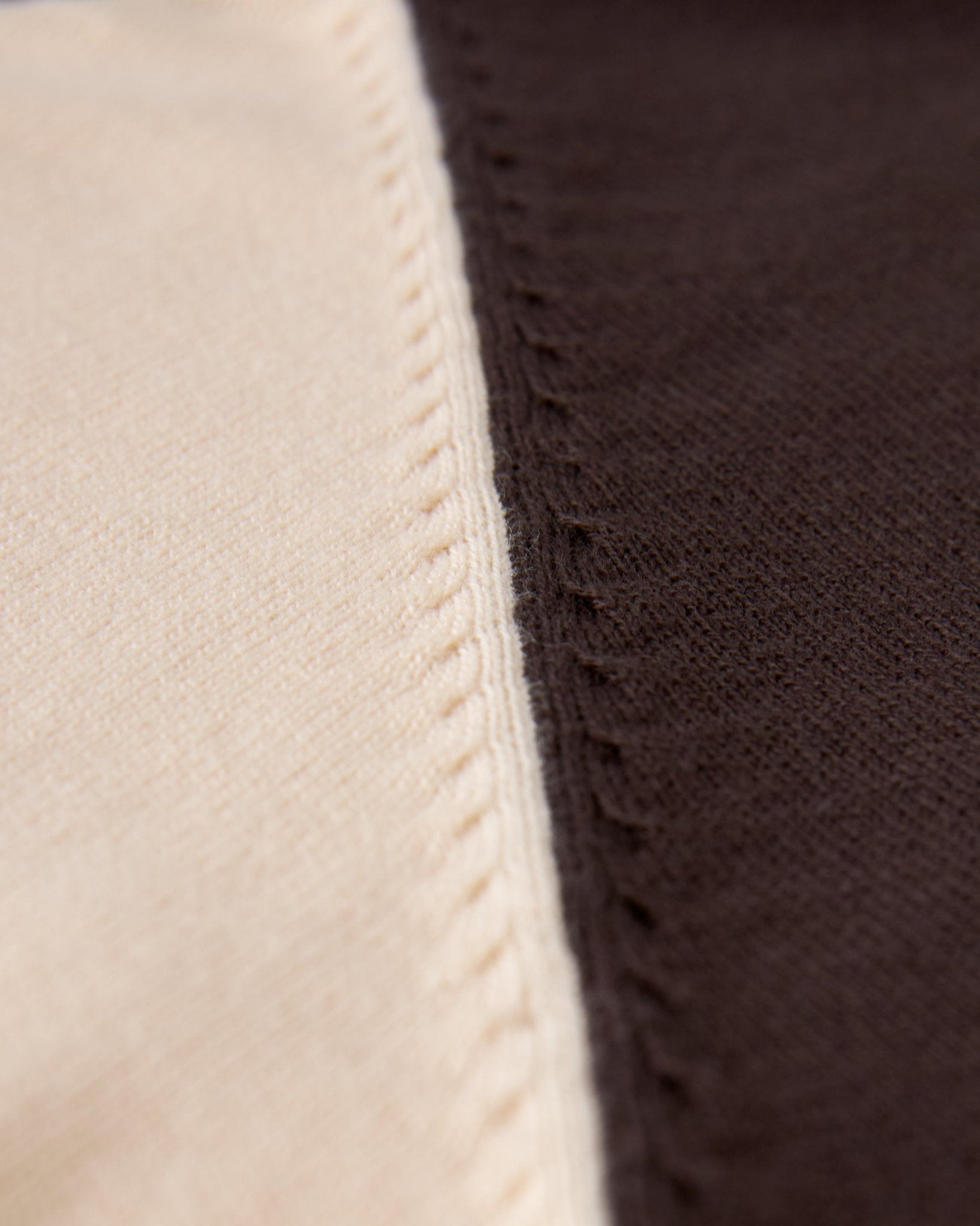 Close-up of beige and dark brown knitted fabric, illustrating the seam on Dandy Del Mar’s Grenada Sweater Knit Baseball Tee - Tierra and evoking its vintage-sport charm and lightweight cotton comfort.