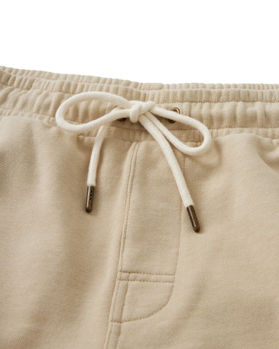 Close-up of The Marseille French Terry Shorts in Ginger by Dandy Del Mar, featuring a beige hue, elastic waistband, white drawstring bow, and visible side pocket.