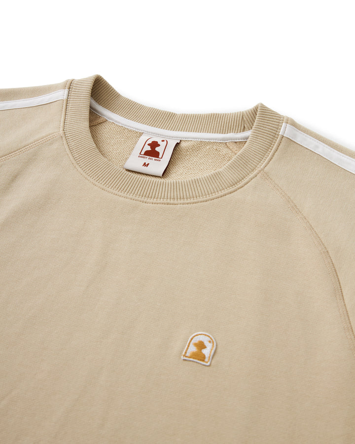 A tan sweatshirt with a white Dandy Del Mar Marseille Pullover - Ginger logo on it.