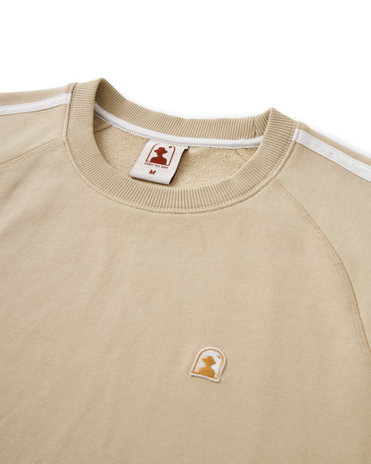 The Marseille French Terry Pullover - Ginger by Dandy Del Mar is a beige 100% cotton raglan crewneck sweatshirt with white stripes along the shoulders and sleeves, and features a small icon of a silhouette on the chest and neck tag.