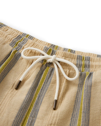 Close-up of The Corralejo Shorts - Ginger by Dandy Del Mar: beige crinkle gauze with blue and green stripes, elastic waistband, and white drawstring—perfect summer essential.