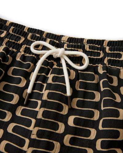 Close-up of The Grenadine Shorts - Truffle by Dandy Del Mar: men's black casual shorts with a tan geometric pattern, white drawstring waistband, and lightweight crinkle gauze for comfort.