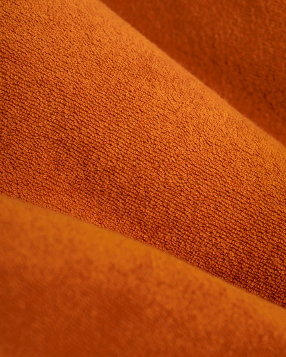 Close-up of The Tropez Robe - Burnt Sienna by Dandy Del Mar, revealing orange textured fabric folds with an intricate pattern and various shades reminiscent of ultra-soft Terry Cloth.