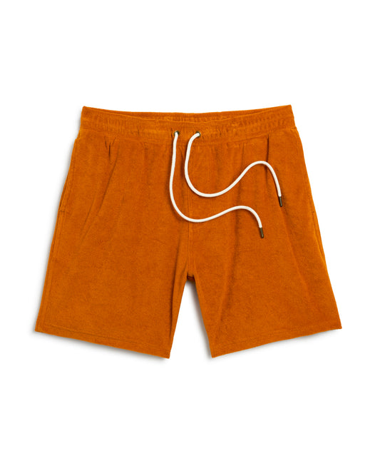 A pair of The Tropez Terry Cloth Short - Burnt Sienna by Dandy Del Mar, featuring an elastic waistband and white drawstring, laid flat on a white background.